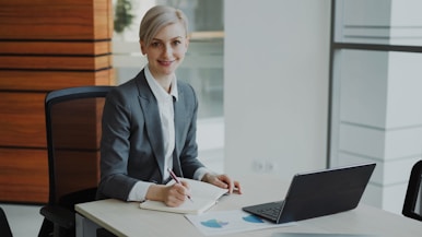 A professional woman in a suit works at a desk.