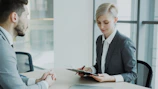 Woman in suit reviews document with man