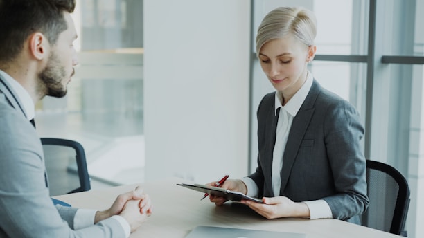 Woman in suit reviews document with man.