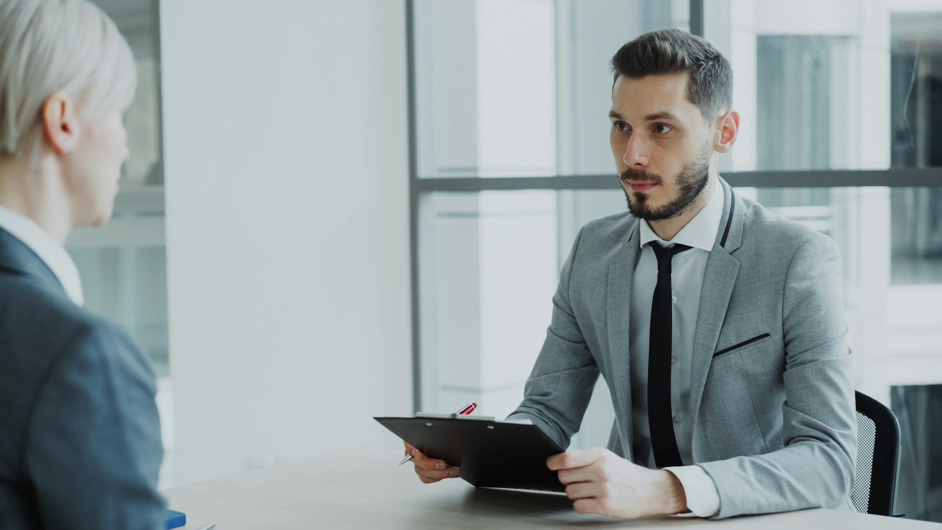 Two people in a business meeting with a clipboard.
