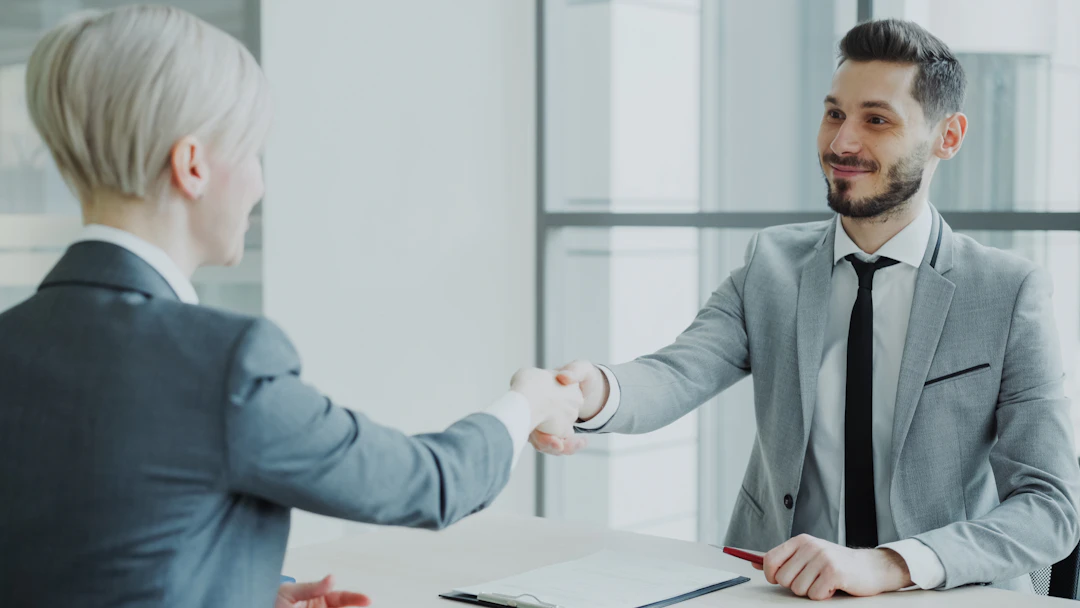 Two professionals shaking hands across a table, representing a successful skilled-professional Golden Visa approval.