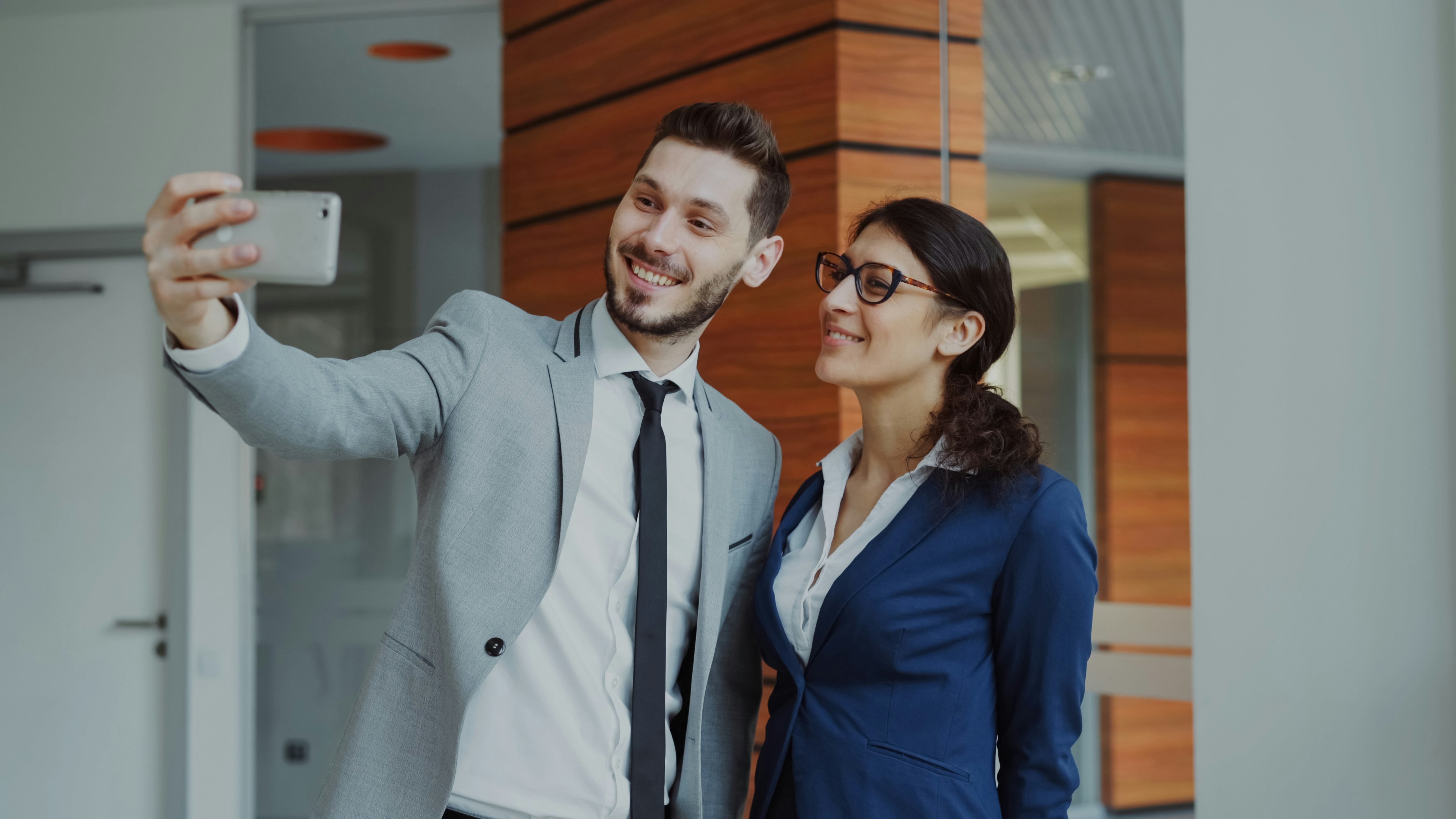 Man and woman taking a selfie in office building.