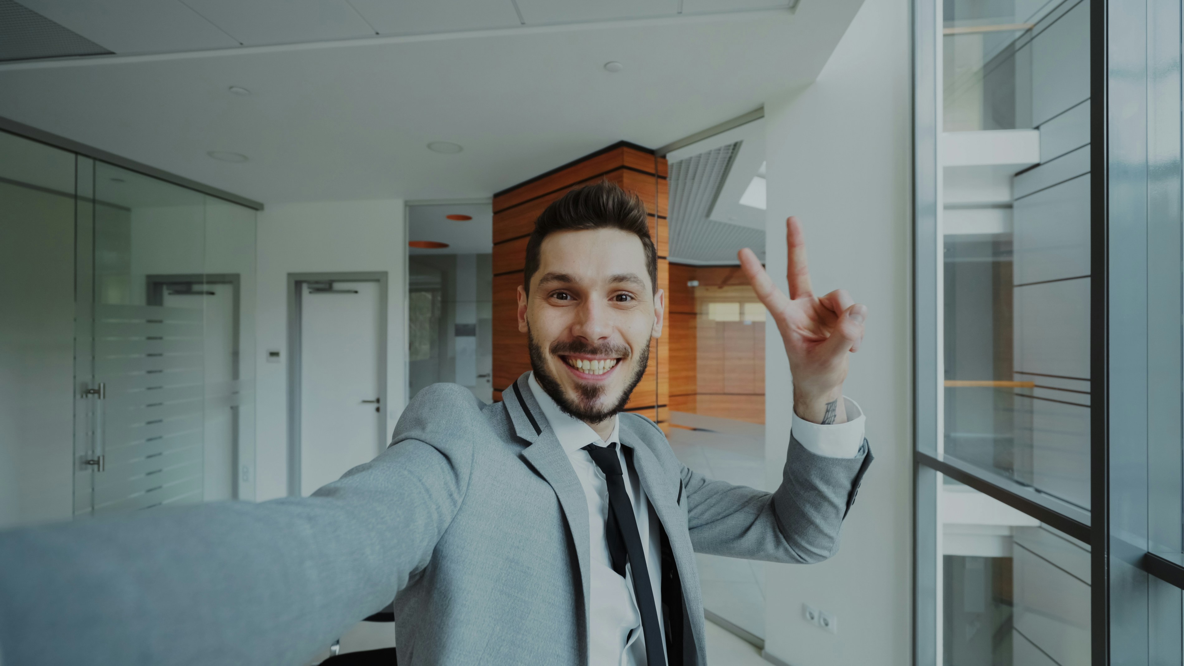 Man in suit taking a selfie and making peace sign.