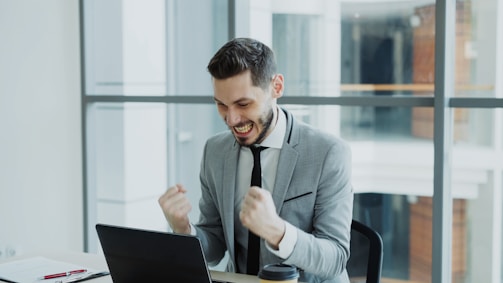 Man celebrating success while looking at laptop.