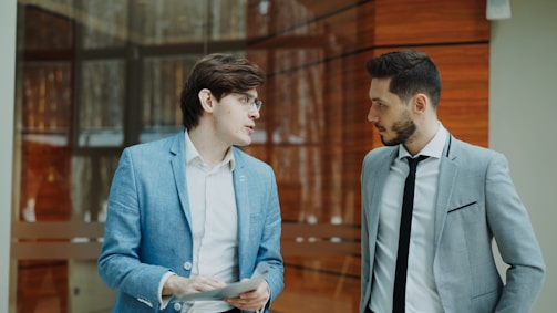 Two businessmen in suits talking indoors