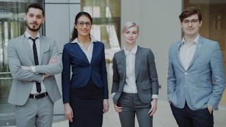 Four business professionals standing together indoors.