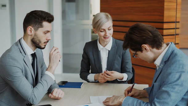Business people signing a contract at a table.