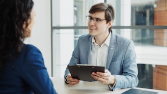Man in suit interviews woman holding clipboard.