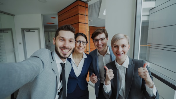 Four smiling business people taking a selfie together.
