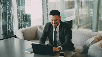 Man in suit smiling while using a laptop