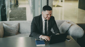 Man in suit working on laptop at a table.