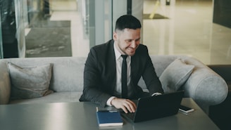 Man in suit working on laptop at a table.
