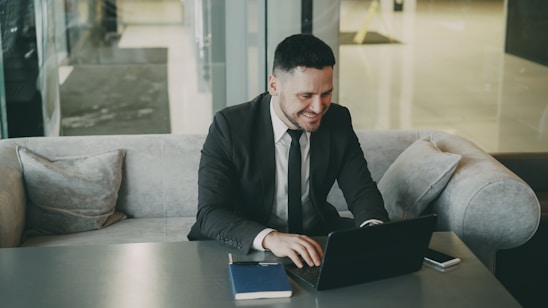 Man in suit working on laptop at a table.