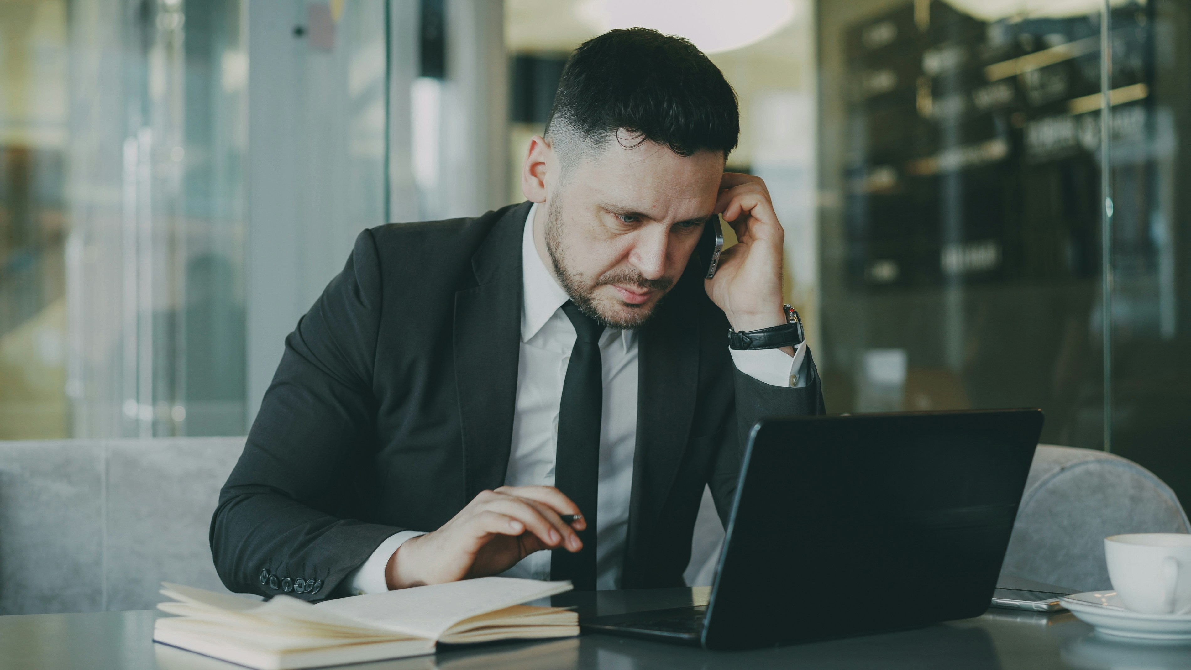 Businessman taking notes while on phone