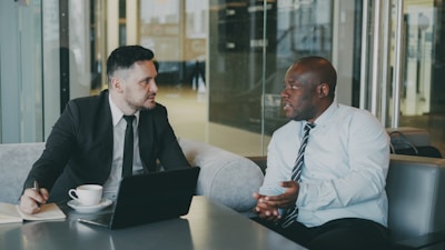 Two businessmen in suits talking in a modern office.