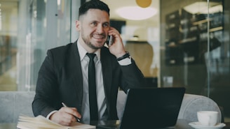 Man in suit talking on phone at laptop