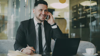 Man in suit talking on phone at laptop