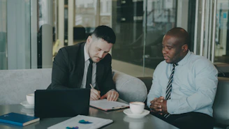 Two businessmen signing a document at a table.