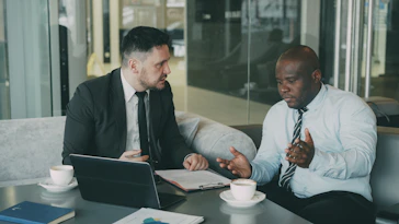 Two businessmen discussing documents at a table.