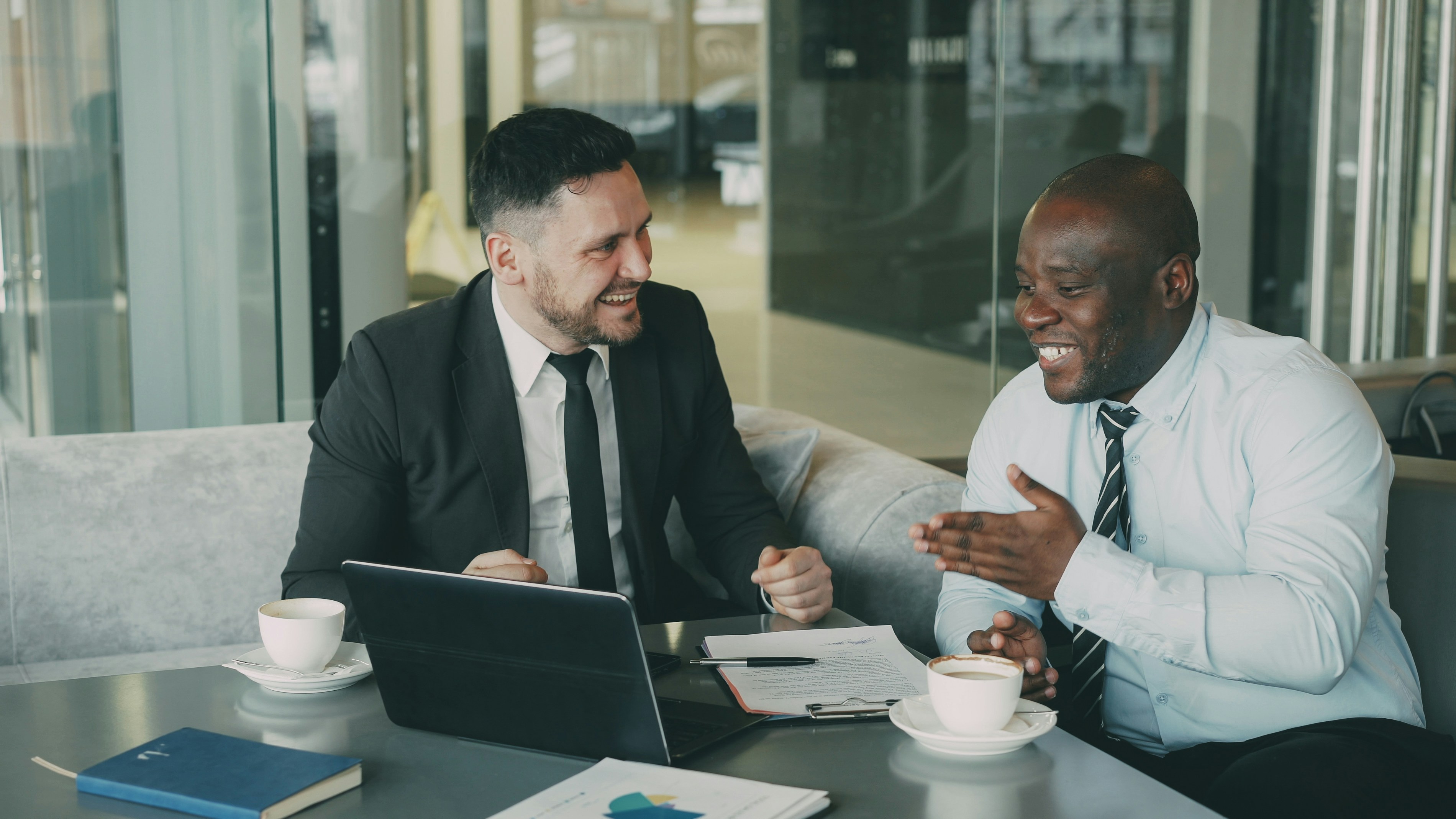 Two businessmen laughing during a meeting at a cafe