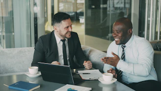 Two businessmen laughing during a meeting at a cafe.