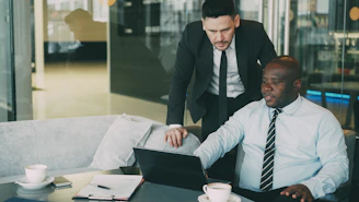 Two businessmen collaborating on a laptop in an office