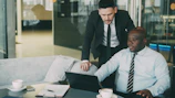 Two businessmen collaborating on a laptop in an office.