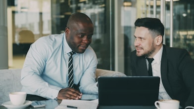 Two businessmen discussing documents at a table.