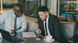 Two businessmen reviewing documents at a table.