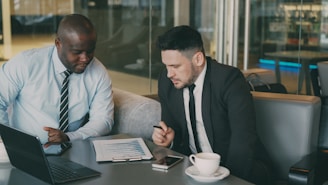 Two businessmen reviewing documents at a table.