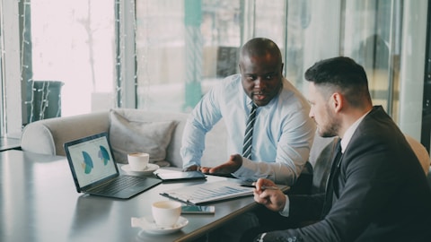 Two businessmen discussing charts on a laptop.