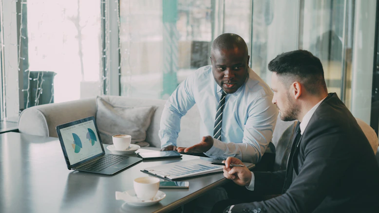 Two businessmen discussing charts on a laptop