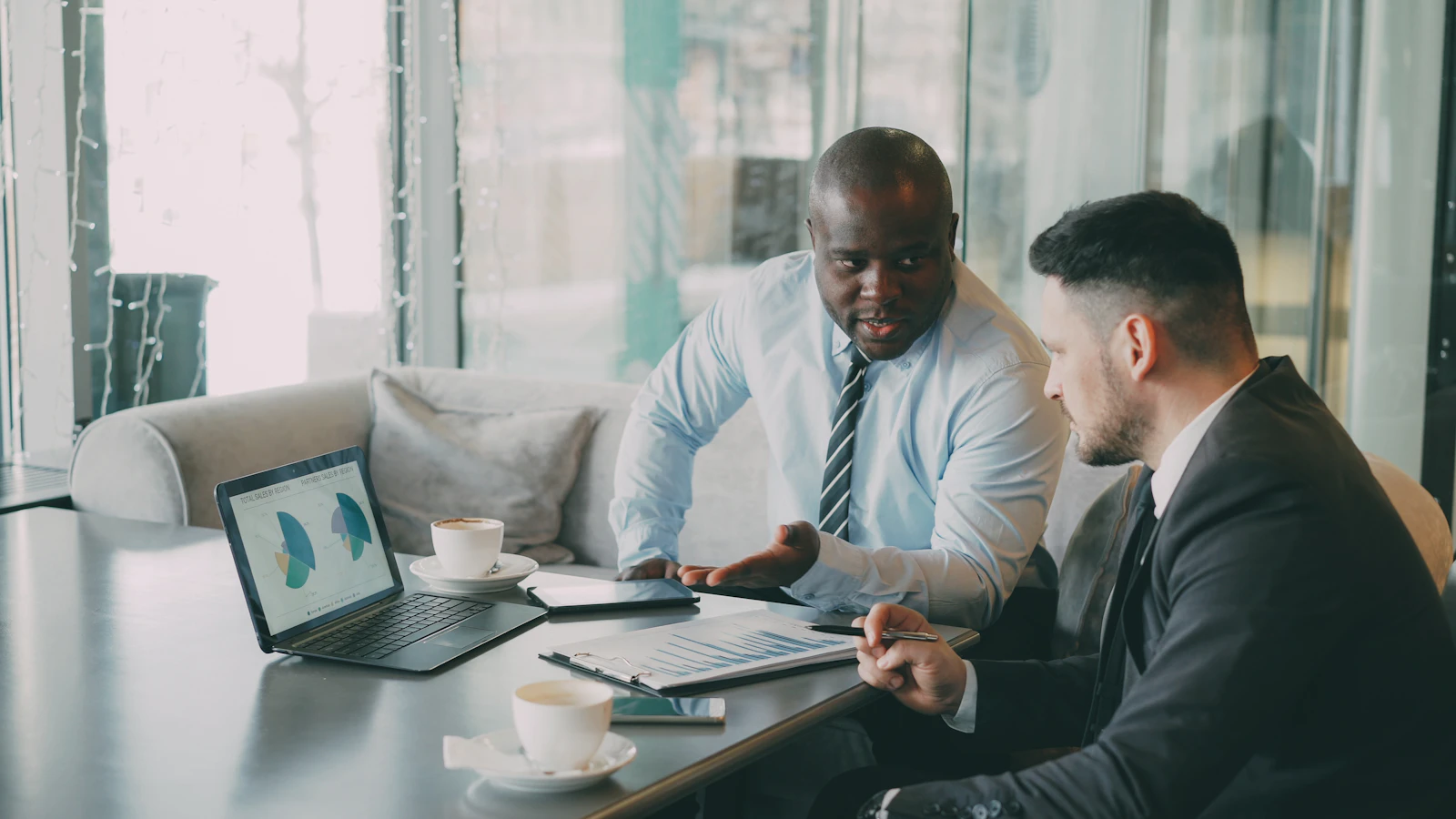 Two analysts reviewing charts together on a laptop