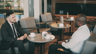 Two men in suits talking at a cafe