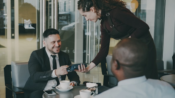 Customer paying with a card at a cafe table, representing a typical Square POS transaction