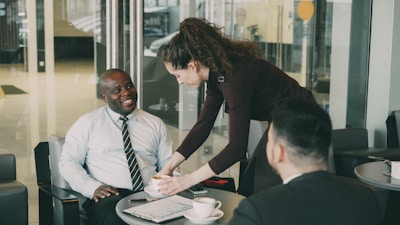 Woman serves coffee to men in office lobby.