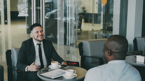 Two businessmen talking over coffee at a table.