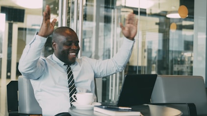 Man in office celebrating success with laptop