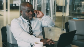 Man talking on phone while working on laptop