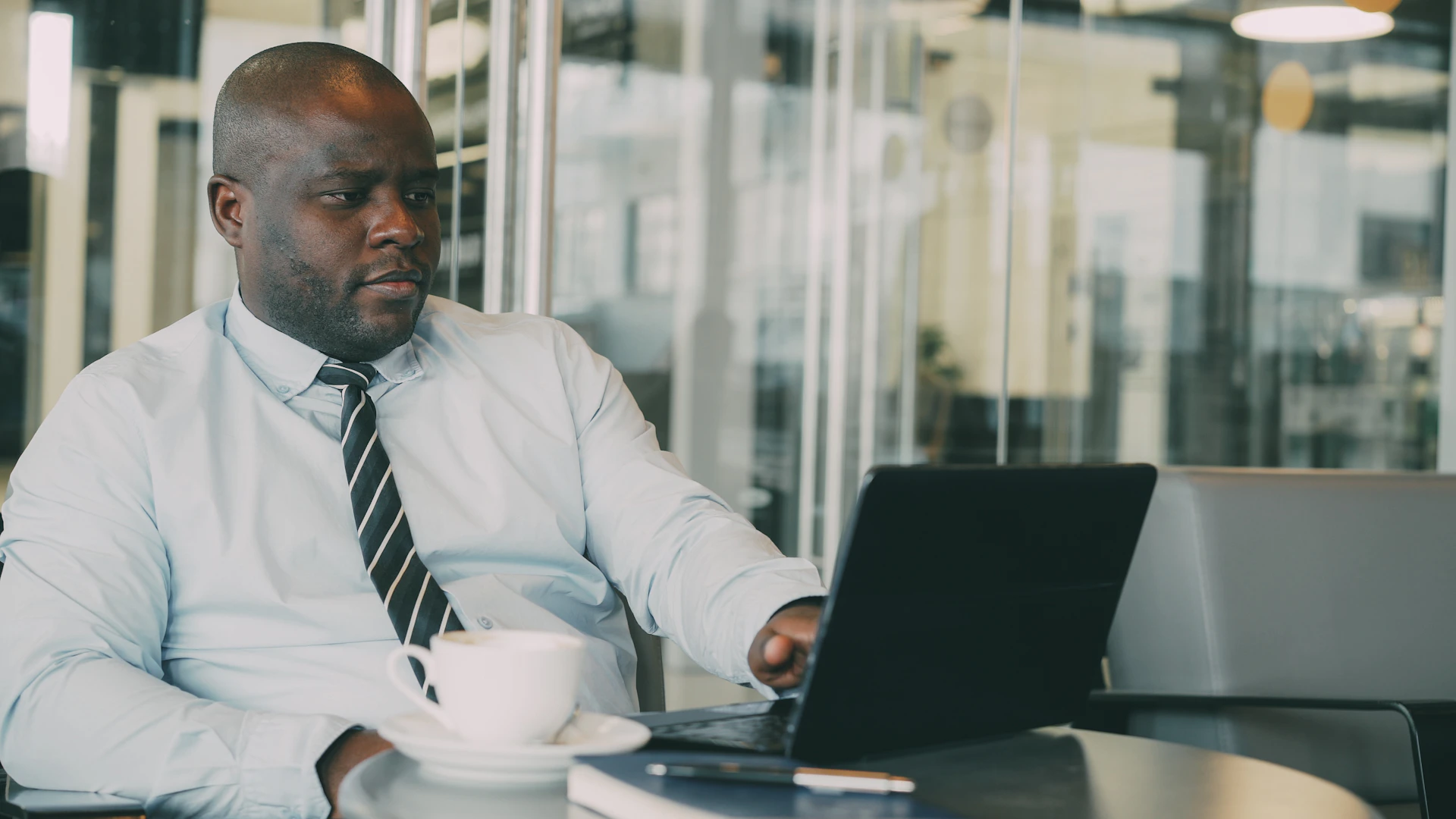 Man in a suit working on a laptop with coffee.