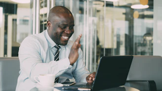 Man waving during a video call on laptop.