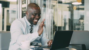 Man waving during a video call on laptop.