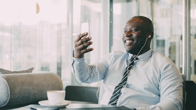 Man smiling while holding phone with earbuds in