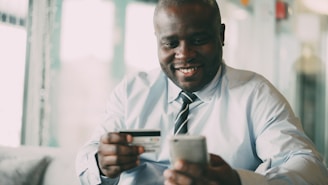 Man smiling while holding credit card and phone