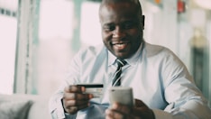 Man smiling while holding credit card and phone