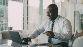 Man with credit card using laptop with coffee.