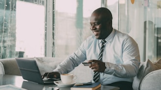 Man with credit card using laptop with coffee.