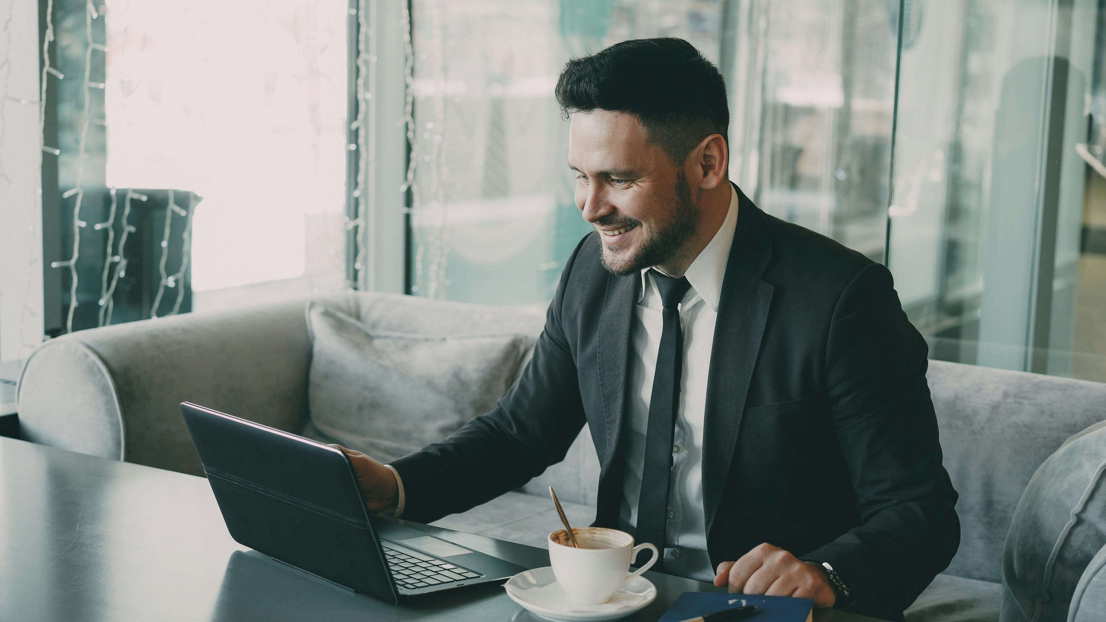 Cheery bearded Caucasian businessman in formal clothes chatting to his family through laptop