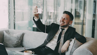 Man in suit taking a selfie on a couch.