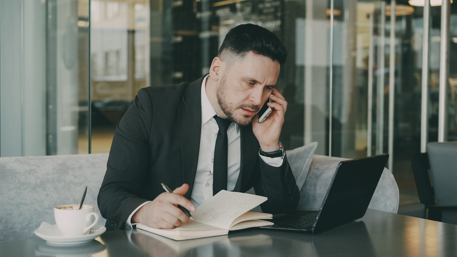 Dirigeant de PME B2B au téléphone qui prend des notes sur un carnet pendant un appel de qualification de cible commerciale